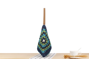 Detail of hand-woven crochet tote bag with navy green patterns and brown leather handle