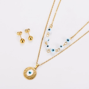 Detail of gold evil eye jewelry set with layered necklace and round hammered pendant