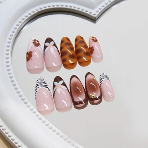 Almond press-on nails with leopard print and floral designs on heart mirror