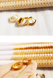 Detail view of mini gold hoop earrings with enamel inlay in brown and white shades