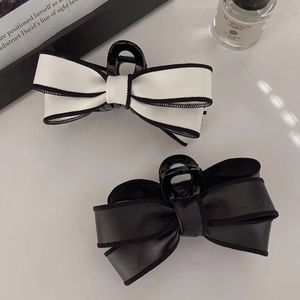 Detail view of large leather bow hair claws in contrast black and white on a book