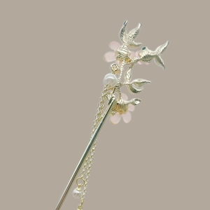 Detail of golden floral hair stick with pink petals, pearls, and flowing tassels