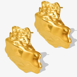 Detailed macro view of 18K gold earrings with irregular punk rock texture and metallic finish