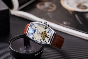 Detail view of the silver tonneau case, moon phase dial, and open-heart movement window