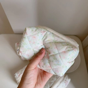 Detailed close-up of quilted floral cosmetic bag with diamond patterns and zipper