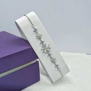 Silver four-leaf clover bracelet with white cat-eye stone and star charms in a purple gift box