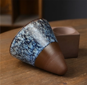 Detail of a Japanese-style handmade ceramic mug with blue mottled glaze and raw clay base