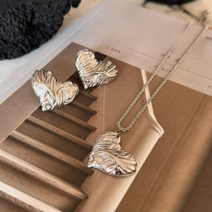 Detailed view of silver heart-shaped jewelry set with vintage embossed texture on magazine