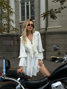 Close-up of elegant V-neckline and tiered ruffle details on a white chiffon mini dress
