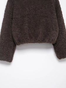 Detailed close-up of dark brown faux shearling fabric with elasticated hem and cuffs
