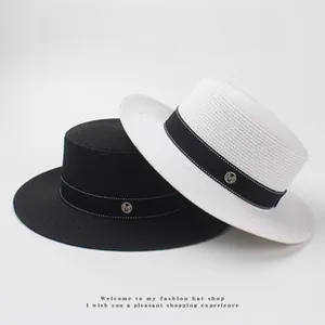 Detailed view of woven boater hats featuring a black ribbon and metallic M emblem