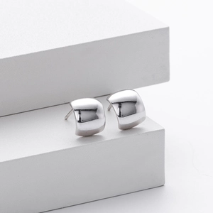 Detalle macro de pendientes de arco de plata S925 minimalistas con acabado de espejo pulido
