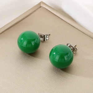Detailed view of green crystal ball earrings on a metallic tray with titanium steel pins