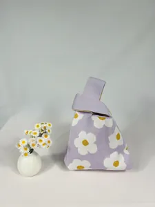 Detail of purple knitted bucket bag featuring white and yellow daisy flower patterns