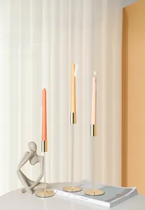 Detailansicht von drei goldenen Metallkerzenhaltern in verschiedenen Höhen auf einem Tisch