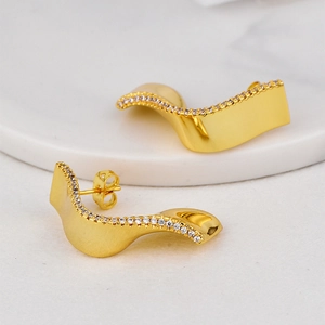 Irregular geometric wavy gold earrings with pavé white zircon stones in minimalist style