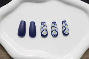 Detailed view of matte navy long coffin press-on nails with white daisy floral patterns