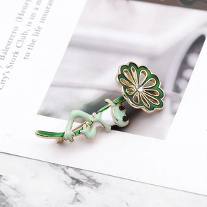 Detail of frog with flower umbrella enamel brooch featuring a rhinestone on open book pages
