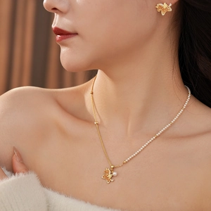 Close-up of golden butterfly necklace and earrings set with pearls and zircons on a model