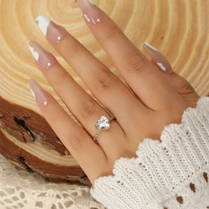 Detail of gold-plated heart-cut zircon ring with pavé-set side stones on lace