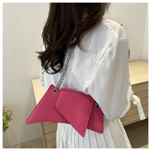 Detail view of pink geometric leather bag with silver chain strap on white dress