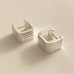 Macro view of 925 sterling silver square earrings with textured parallel ribbed layers