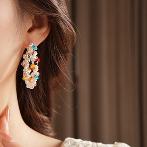 Primo piano di orecchini a cerchio con perle colorate indossati da una modella elegante