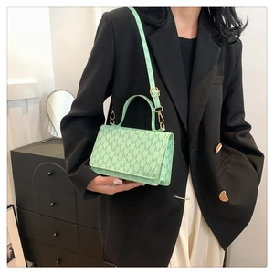 Mint green square handbag with M-letter print and gold hardware worn by model
