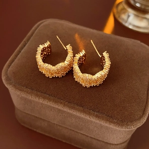 Close-up of gold C-shaped hoop earrings with sparkling cubic zirconia on brown velvet box
