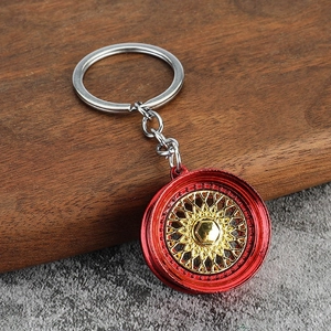 Macro shot of red and gold BBS style car wheel hub keychain on dark wood surface