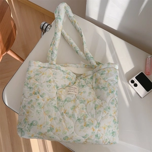 Detailed macro view of quilted floral cotton tote bag with vintage woven brand label