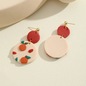 Detailed macro view of polymer clay earrings featuring embossed pumpkin and green leaf patterns