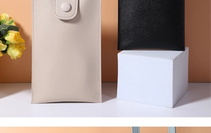Detail of minimalist mini phone bags in beige and black with textured PU leather snap closure