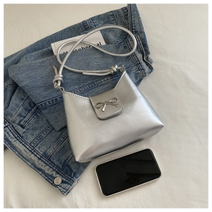Silver bow shoulder bag detail showing knotted strap and smooth metallic finish on white fabric