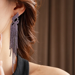 Gros plan de longues boucles d'oreilles à pompons en strass violets sur un mannequin