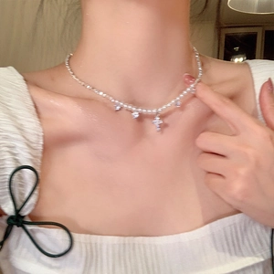 Detailed view of silver bead necklace with zircon cross pendant worn on neck