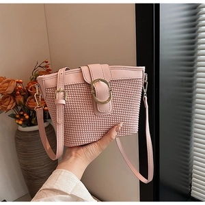 Detail of pink leather and woven bucket bag with elegant golden round buckle closure