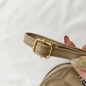Close-up of adjustable beige PU leather shoulder strap with gold-tone metal buckle
