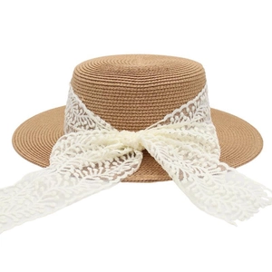 Détail d'un chapeau canotier en paille avec ruban de dentelle blanc et grand nœud chic