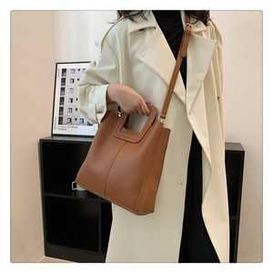 Close-up of caramel brown leather bucket bag with top handle and adjustable strap