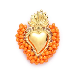 Close-up of heart-shaped stainless steel pendant with orange beads and gold finish