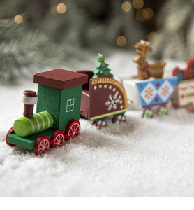 Detail of wooden Christmas train toy with painted reindeer and tree on snowy background