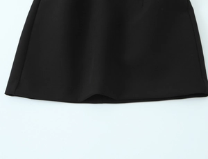 Detailed close-up of the black polka dot dress hemline showing smooth polyester fabric
