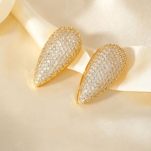 Boucles d'oreilles goutte dorées avec zircons pavés sur un tissu en soie luxueux
