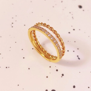 Detailed close-up of double-layer gold ring with twisted rope design and white diamonds