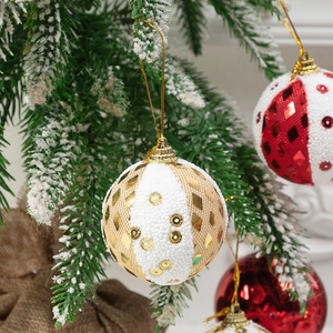 Glittering white and gold foam Christmas ball ornaments hanging on a snowy tree branch