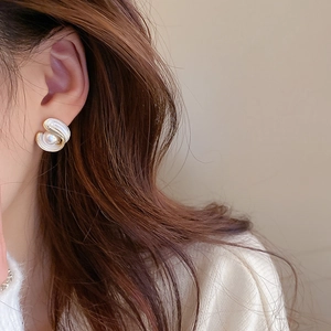 Detail showing vintage pearl earrings with gold spiral edges worn by a female model