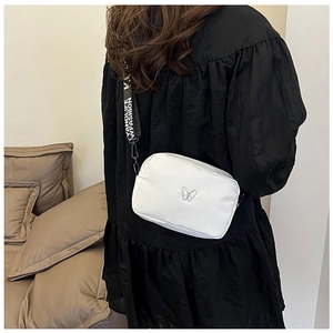 Detail of white nylon square bag with metal butterfly and branded wide shoulder strap