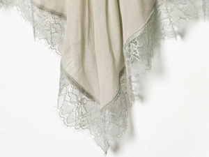 Detail of silk fabric with delicate lace trim in champagne and sage green tones