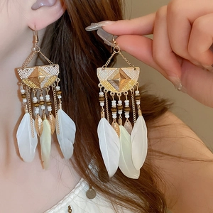 Detail of bohemian drop earrings with white feathers, beads, and gold leaf pendants